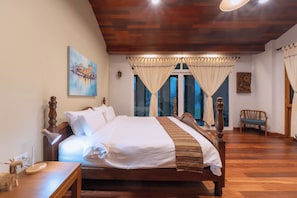 A bedroom with a wooden bed, a nightstand, a lamp, a chair, and a painting on the wall.