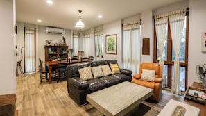 A living room with a leather sofa, a coffee table, and a dining area with a wooden table and chairs.