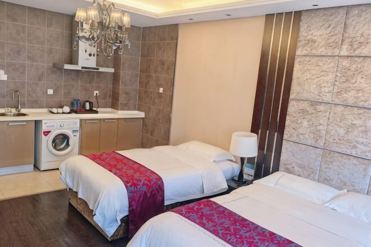 A hotel room with two beds, a washing machine, a chandelier, and a marble wall.
