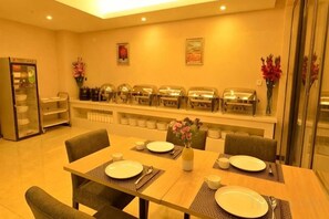 A dining area with a buffet setup, a refrigerator, and a vase with flowers. - Carnival CEO Hotel (Chengdu Tianfu 3rd Street Funian Square) (Chengdu)