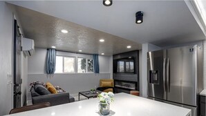 Una cocina moderna con una isla grande, electrodomésticos integrados y una zona de estar con un sofá y una silla.