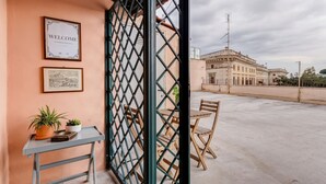 Un balcon avec une grille en métal, une pancarte de bienvenue, des photos encadrées et une table avec des chaises.