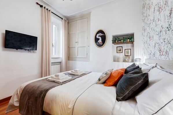 A bedroom with a bed, a flat-screen TV, a door, and a window. - Penthouse Brancaccio - Wide Panoramic Terrace (Roma)