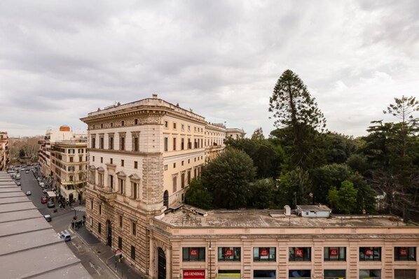 A multi-story building with classical architecture, a street in front, and trees in the background.