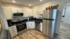 A modern kitchen with white cabinets, stainless steel appliances, and a wooden floor. - Mountain Bluebird Condo Getaway at Schweitzer Ski Resort (Sandpoint)