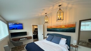 A modern bedroom with a bed, TV, and artwork. - Mountain Bluebird Condo Getaway at Schweitzer Ski Resort (Sandpoint)