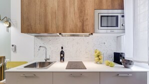 Una cocina con un lavamanos, un microondas y un salpicadero de mármol.
