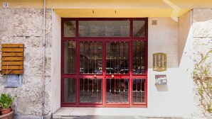 Entrada de un edificio con puerta roja, con los números 15 y 16, y un buzón a la derecha.