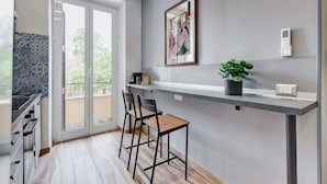 Une cuisine moderne dotée d’une porte-fenêtre coulissante, d’un plan de travail en marbre et d’une œuvre d’art encadrée accrochée au mur.