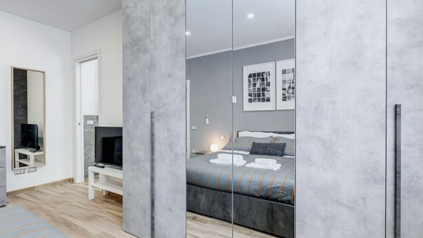 Une chambre moderne avec un grand lit, une télévision, un miroir et une armoire.
