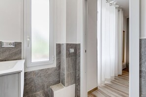 Un baño con lavamanos, ventana y zona de ducha.