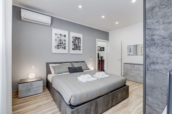 Un dormitorio moderno con cama, mesita de noche y unidad de aire acondicionado de pared.
