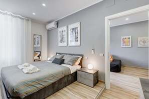 Un dormitorio moderno con cama, mesitas de noche y obras de arte en las paredes.