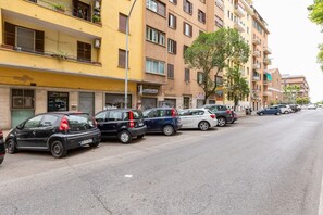 Una calle flanqueada por vehículos estacionados y edificios de varios pisos con balcones.