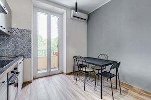 Una cocina con estufa, una mesa de comedor con sillas y un ventanal corredero que da a un espacio exterior.