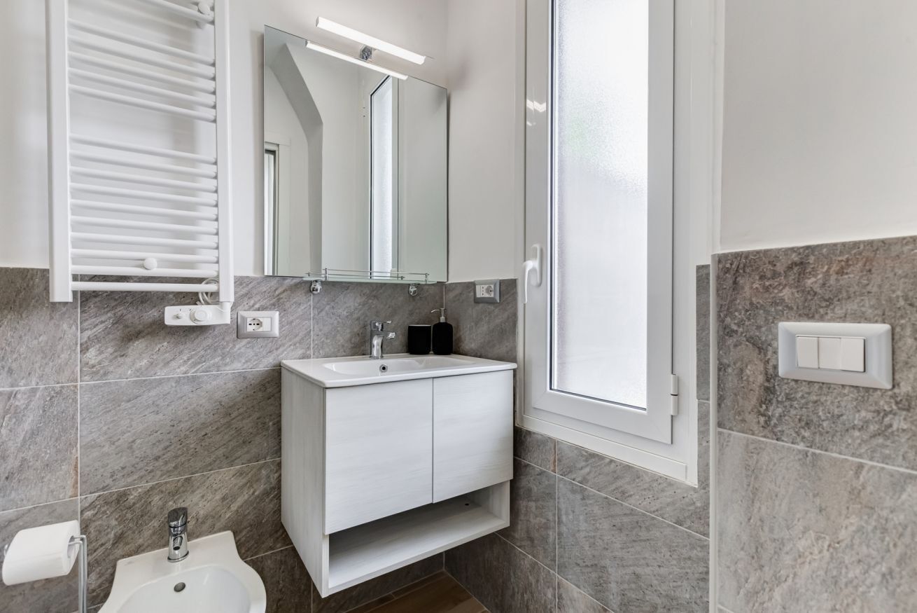 Une salle de bain moderne avec un meuble-lavabo blanc, un miroir, un porte-serviettes et un espace douche.