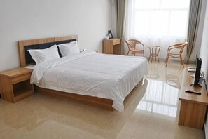 A neatly arranged hotel room with a bed, bedside tables, a desk, two chairs, and a TV. - Dongdaihe Jinxin Holiday Hotel (Suizhong)