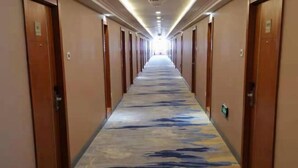 A long, narrow hotel corridor with doors on both sides and a patterned carpet. - Jiejiang International Hotel (Luobei)