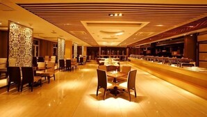 A spacious hotel lobby with a central seating area, a long reception desk, and a modern ceiling design. - Jiejiang International Hotel (Luobei)