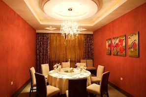 Ein Esszimmer mit einer Chandelüster, einem runden Tisch und Stühlen.