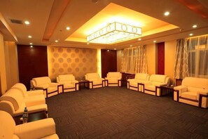 Un espace de détente circulaire, avec des canapés et des tables, un mur orné de motifs et un lustre.