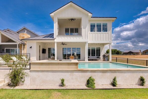 A two-story house with a swimming pool, a balcony, and a covered patio area.