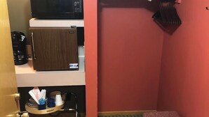 Habitació d'hotel petita i compacta amb un llit superposat, microones, cafetera i una zona de seients reduïda.