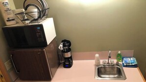 Une petite cuisine équipée d’un four à micro-ondes, d’une machine à café et d’un évier.