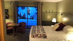 Une chambre d’hôtel avec un lit, un bureau, une chaise et une vue sur un paysage enneigé par la fenêtre.