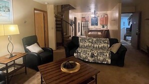 A spacious living room with a high ceiling, a staircase, and a kitchen area. - Ski in/out condo with three queens (Eden)