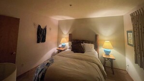 A bedroom with a bed, two bedside tables with lamps, a wall-mounted decoration, and a door. - Ski in/out condo with three queens (Eden)