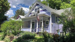 A two-story house with a porch, a flag, and a garden. - Downtown Rustic Luxury Garden Suite (Glenwood Springs)