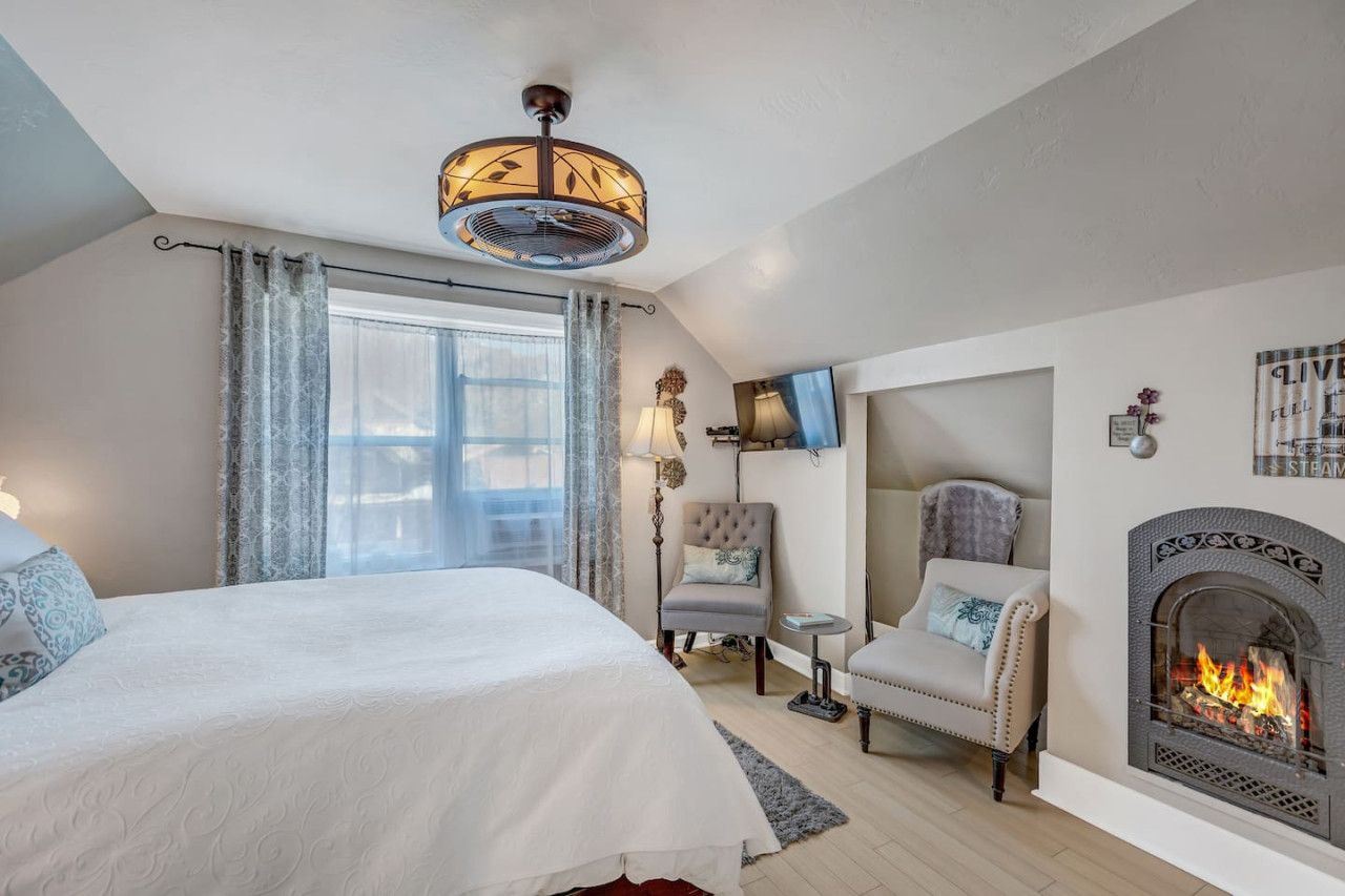 Une chambre à coucher avec un lit, une chaise, une cheminée et une fenêtre.