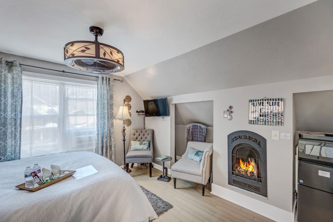 Une chambre d’hôtel équipée d’un lit, d’une cheminée, d’une télévision et d’un ventilateur de plafond.