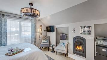 Une chambre d’hôtel équipée d’un lit, d’une cheminée, d’une télévision et d’un ventilateur de plafond.