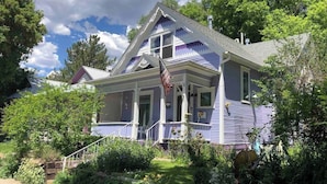 A two-story house with a porch, a flag, and a garden.