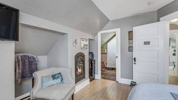 A cozy room with a fireplace, a sofa, a bed, and a television.