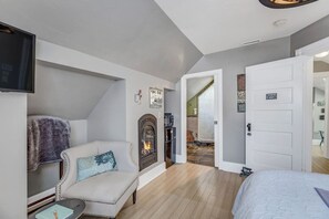 Una habitación acogedora con chimenea, sofá, cama y televisión.