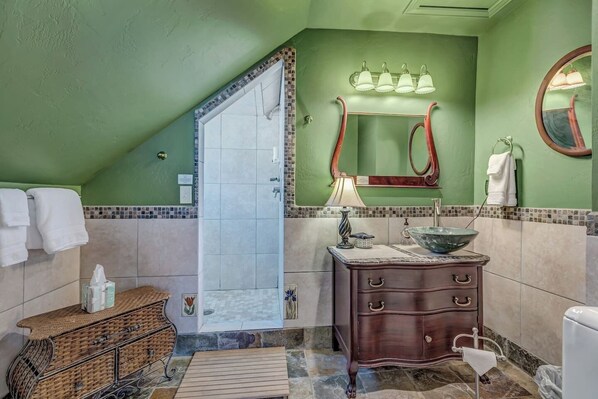 A bathroom with a shower, vanity, and a mirror.