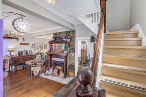 Un salón espacioso con chimenea, escalera de madera y un reloj en la pared.