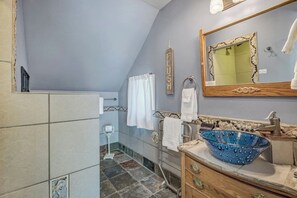 Ein Badezimmer mit einem blauen Mosaikbecken, einer Holzwaschtischgarnitur, einem Spiegel mit dekorativem Rahmen und einem Handtuchhalter.