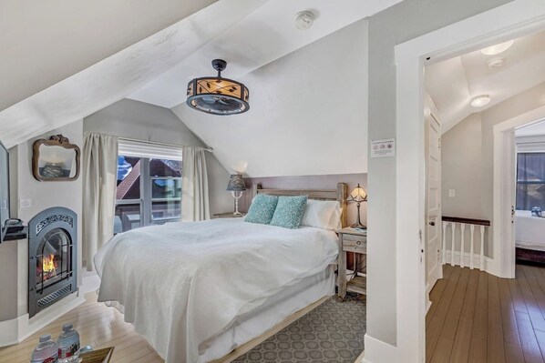 Ein Schlafzimmer mit einem großen Bett, einem Kamin, einem Deckenventilator und Blick ins Freie.