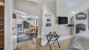 Een gezellige kamer met een open haard, een aan de muur bevestigde televisie en een klein tafeltje met flessen.