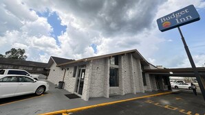 A Budget Inn with a stone facade, a clear sky, and a parking lot with cars.