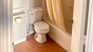A bathroom with a toilet, a bathtub, and a shower curtain.