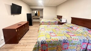 A bedroom with two beds, a dresser, a TV, and a microwave.