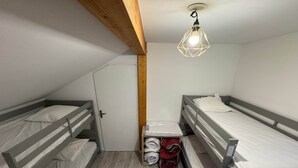 Habitació d'estil dormitori amb llits superposats, una biga de sostre de fusta, una petita prestatgeria amb llençols arrumabats i una làmpada penjant.