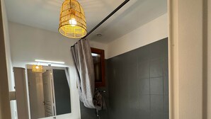 Un bany modern amb una banyera blanca, un lavabo amb mirall i un llum penjant.