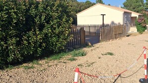A fenced area with a gravel path leading to a building with a beige exterior and a satellite dish.