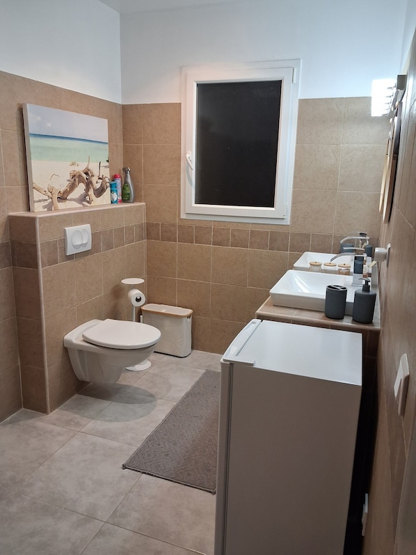 Et lille badeværelse med toilet, vask og et vindue.
